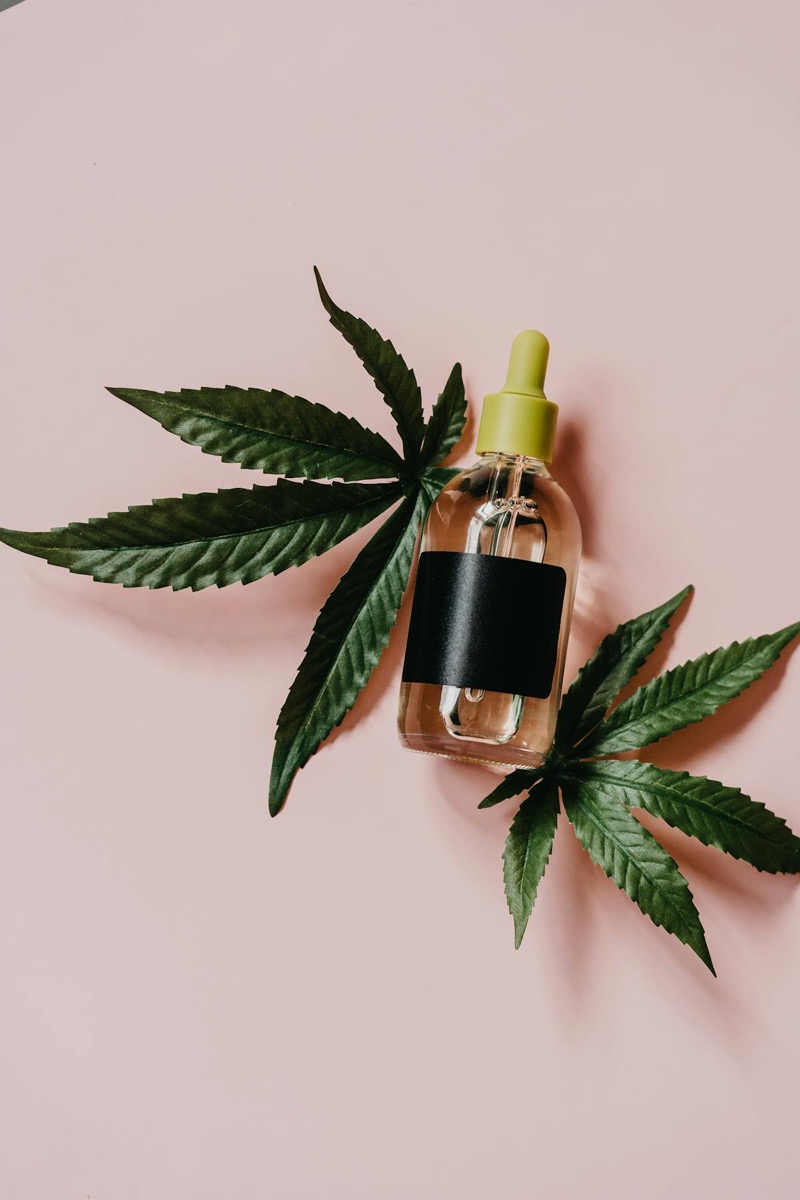 Cannabis CBD oil tincture with dropper beside marijuana leaves